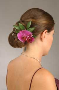 Bridesmaid with her hair pulled in to a low chignon and embelished with an orchid
